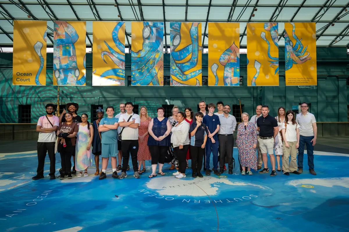 A group of people stand under bright yellow banners with a blue octopus design.