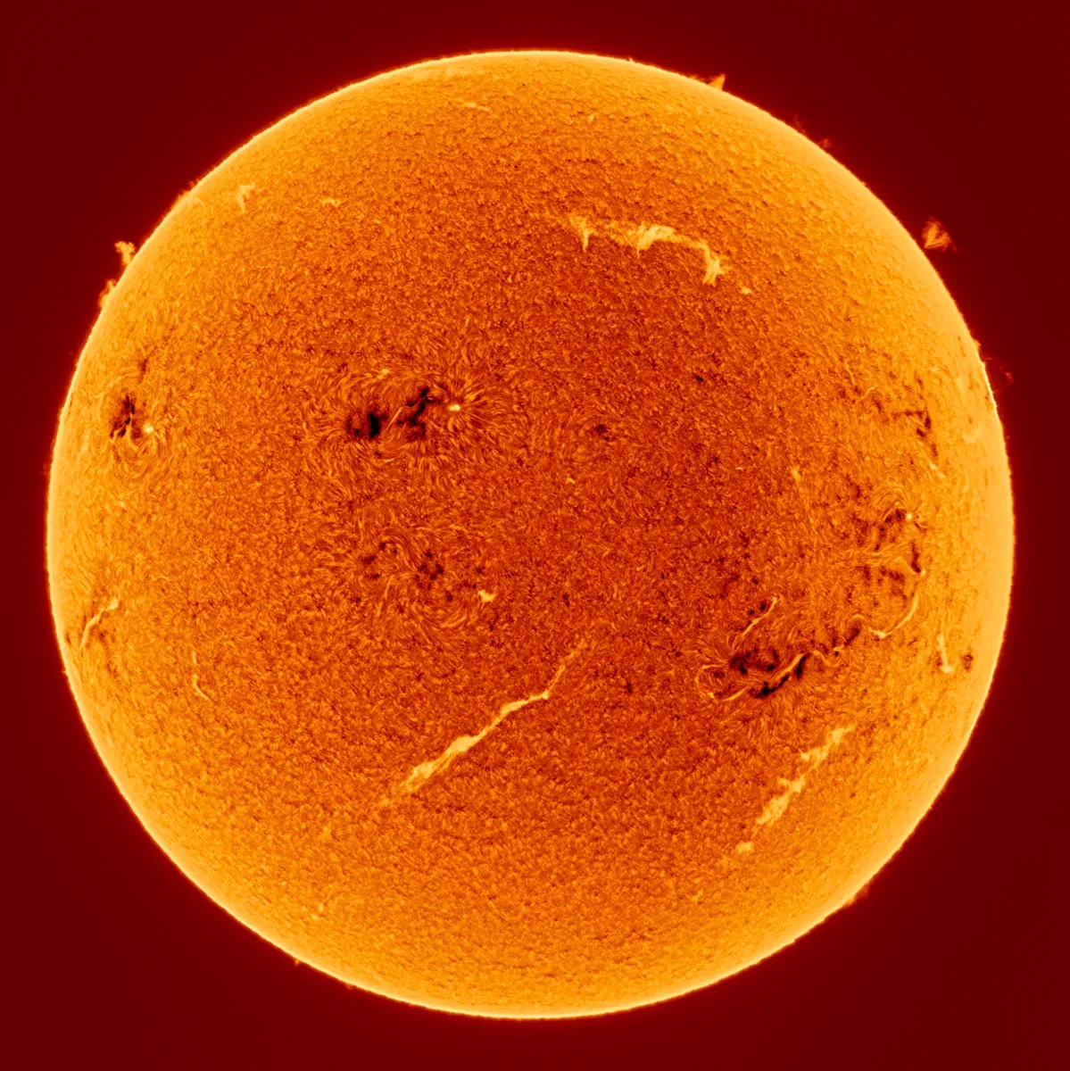 The Sun rendered in varying shades of yellow and red, lighter around the outside and darker orange in the middle. There are a few wispy clouds and sunspots on the surface