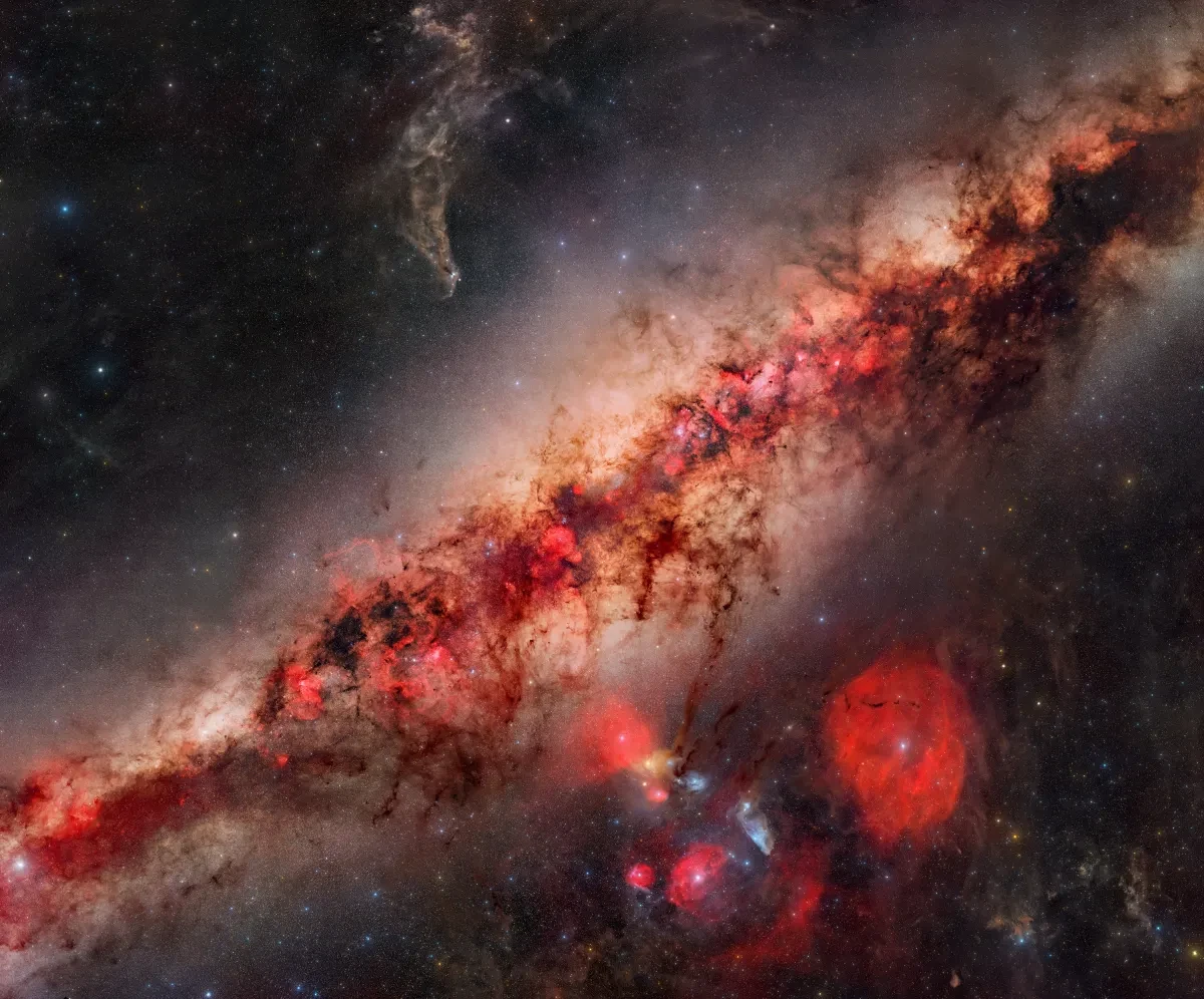 Close up of the Milky Way core, diagonal across the image. The core is rendered in vivid colours in red hues