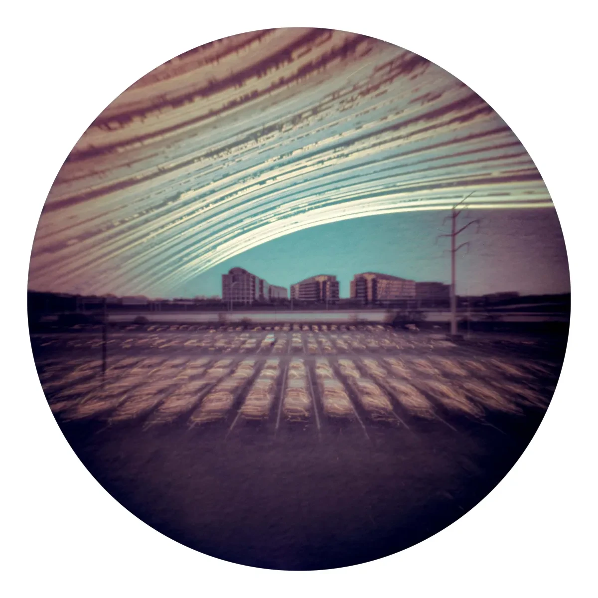 Circular solargraph showing parking lot with scratchy lines resembling car headlight trails and in the sky, multiple curved paths showing the Sun's movement