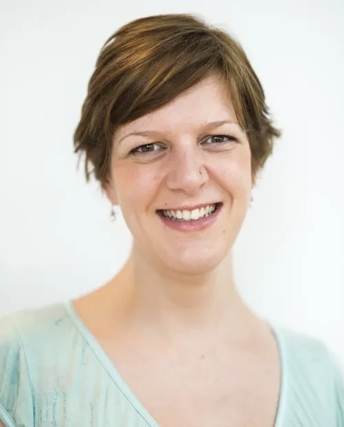 A smiling woman with short brown hair wearing a light green dress