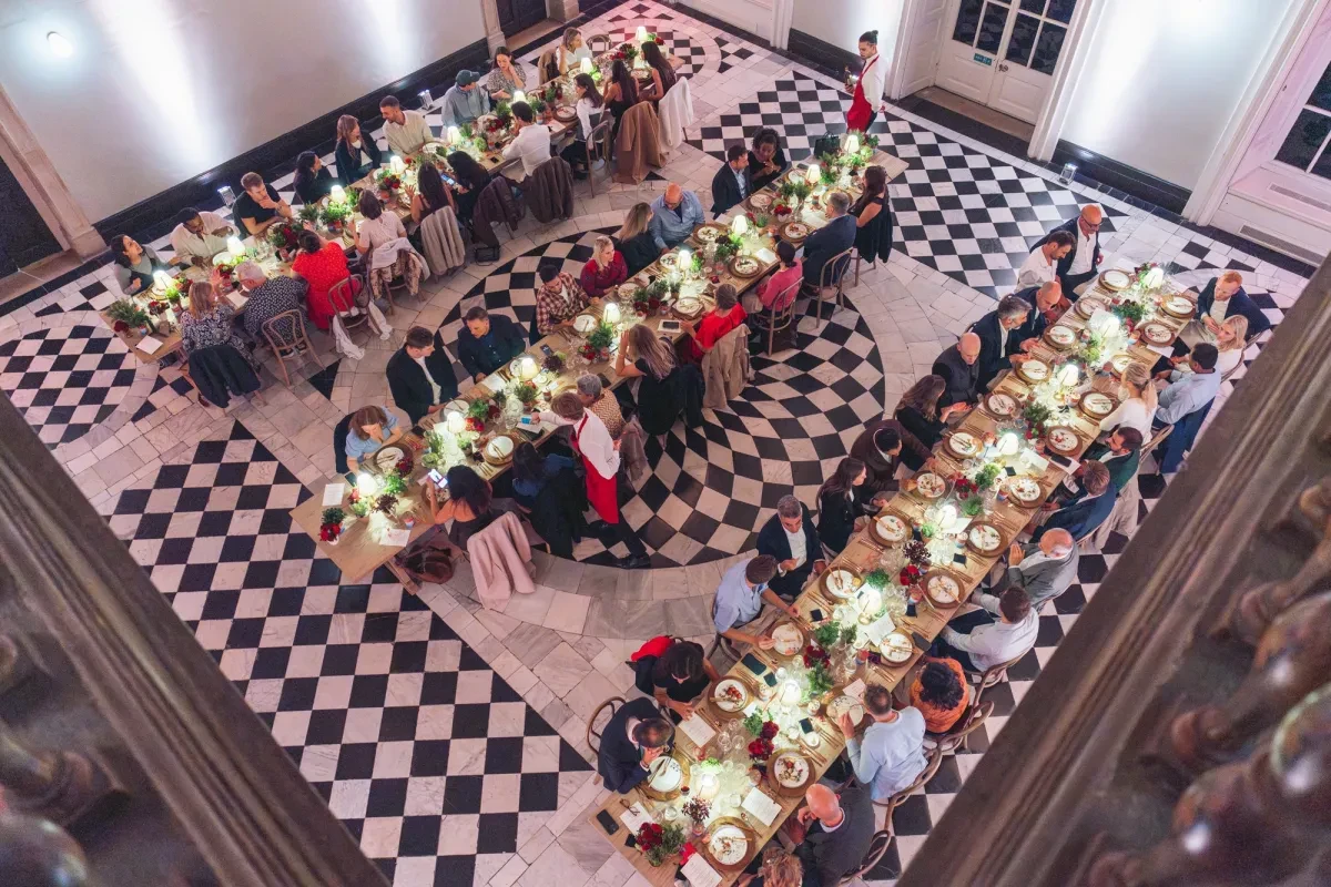 Mutti - 3 long tables set up in the Great Hall on sprigs, with people dining at them
