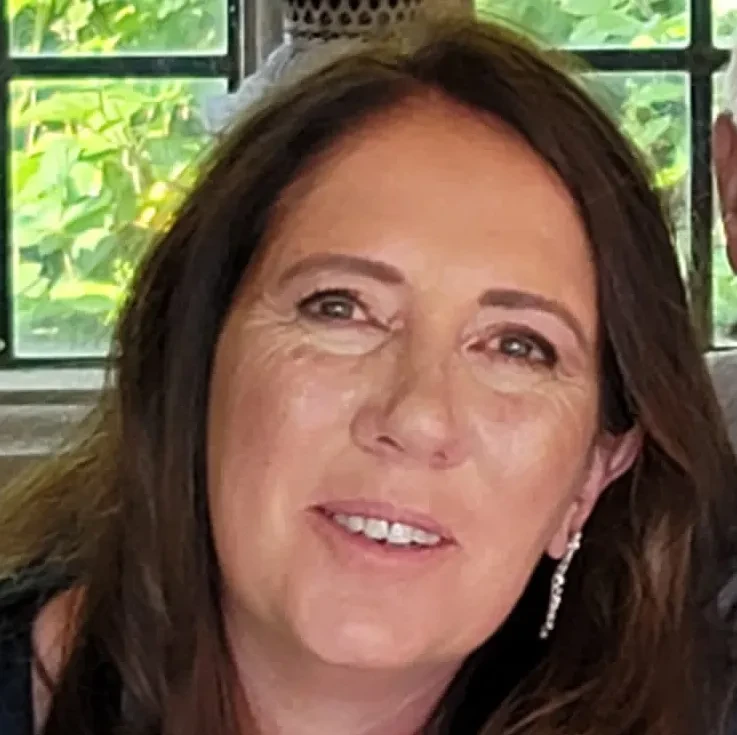 A smiling woman with brown hair wearing long sparkly earrings