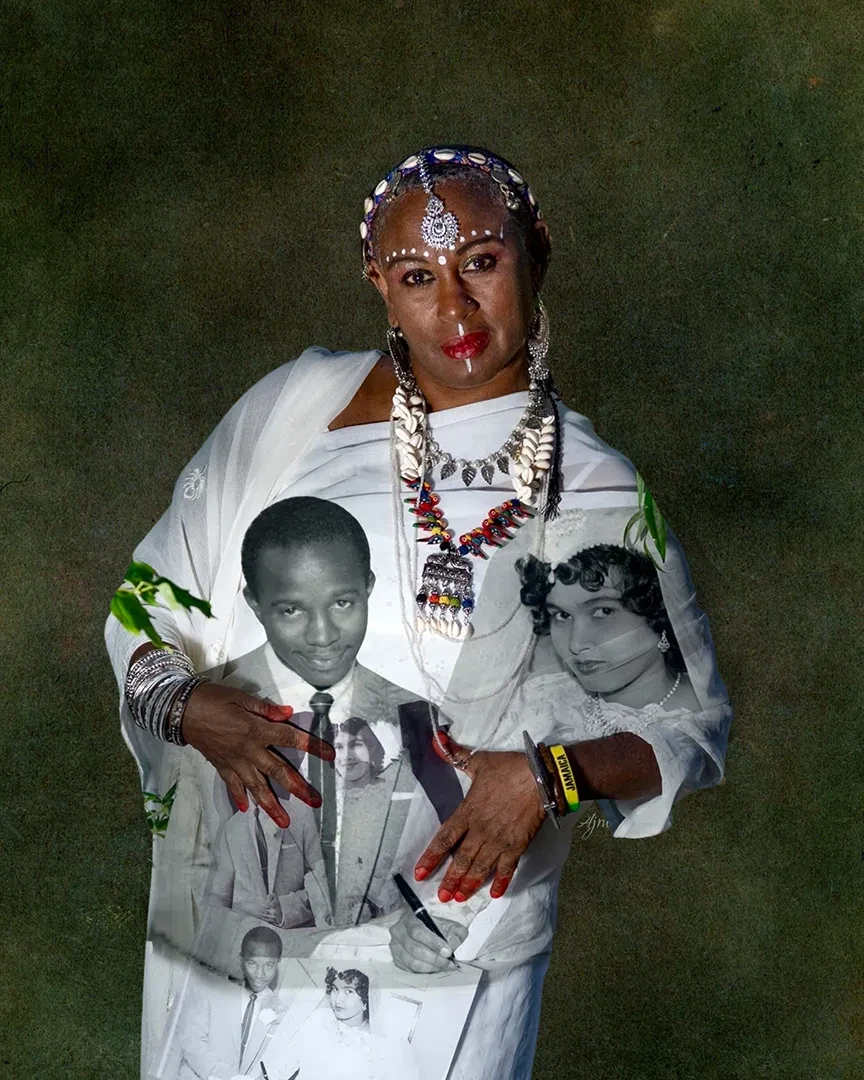 Photographic portrait of a woman wearing ornate head jewellery and necklaces. She wears a white sari-style garment printed with black and white photographs of a man and woman