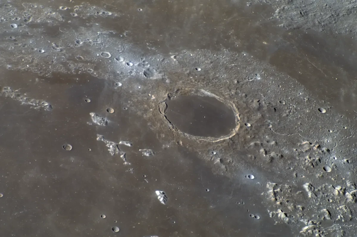 Close up of the Moon's surface with a big central crater surrounded by a mountainous region