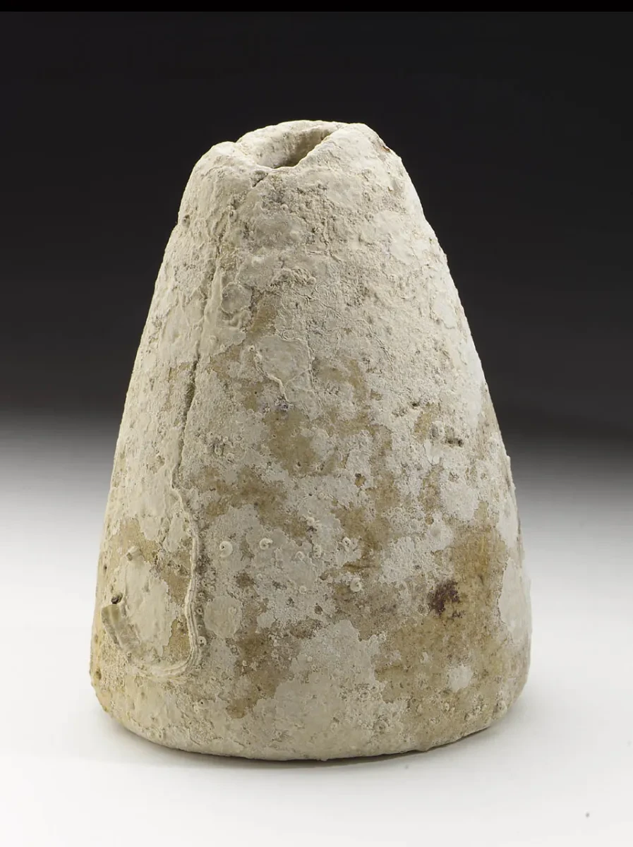 Small Roman pottery flask with a conical body, flat base and narrow opening at the top. The weathered brown ceramic vessel has a simple, rounded shape and uneven surface.