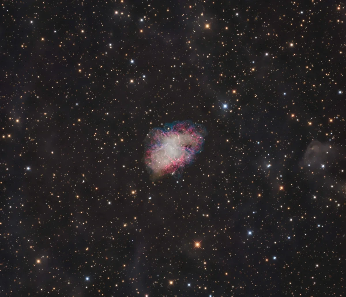 At the centre of a black, star-spotted sky, there's a glowing nebula with red, pink, purple and blue streaks