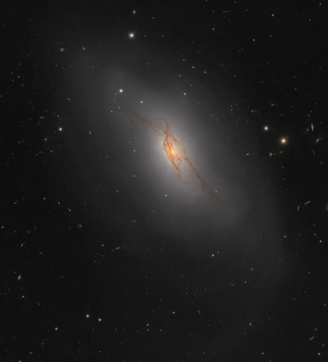 Picture of a lenticular galaxy with orange strands intertwining