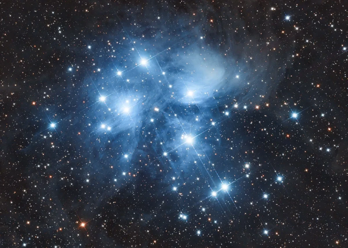 Seven bright white stars shine brightly in a blue black sky dotted with many stars
