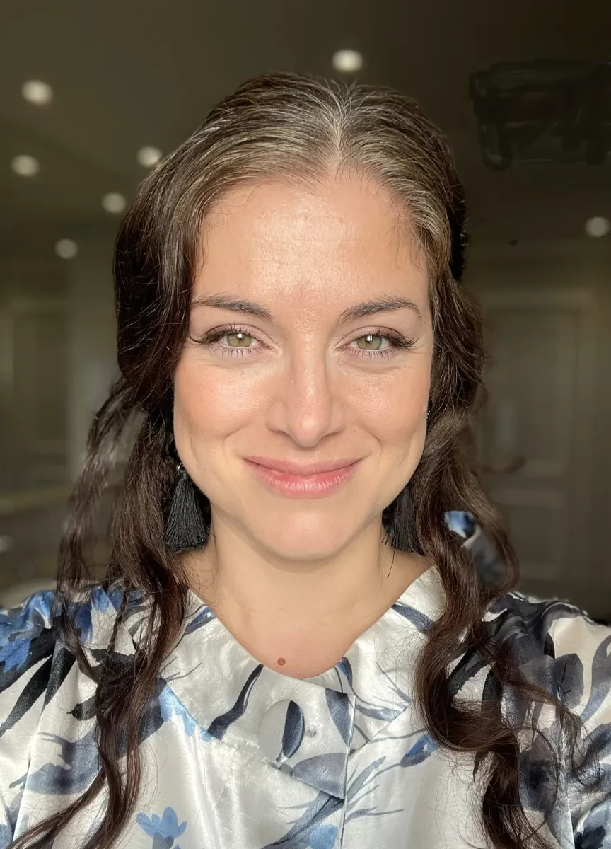 A smiling woman with long, curly brown hair