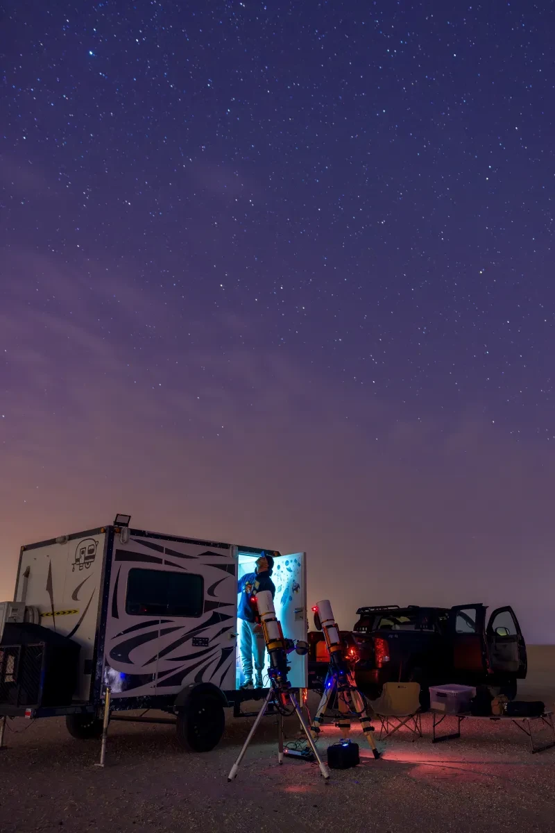 Photo of telescopes next to campervan at night