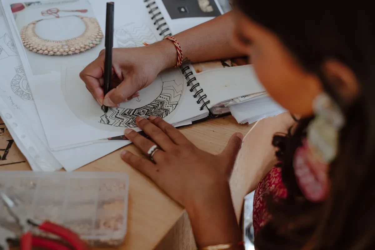 Close up of a person sketching a crescent moon in a sketchbook