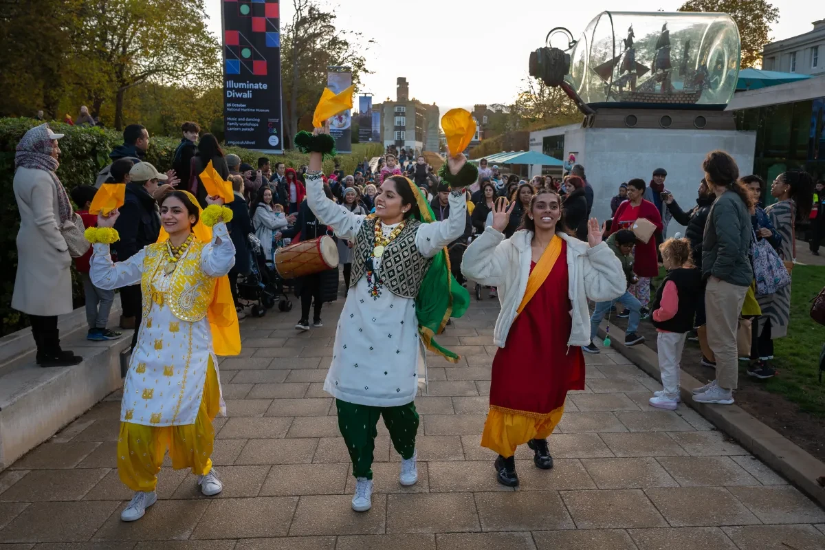Three women in traditional dress dance as part of the Diwali Lantern parade at the National Maritime Museum in Greenwich
