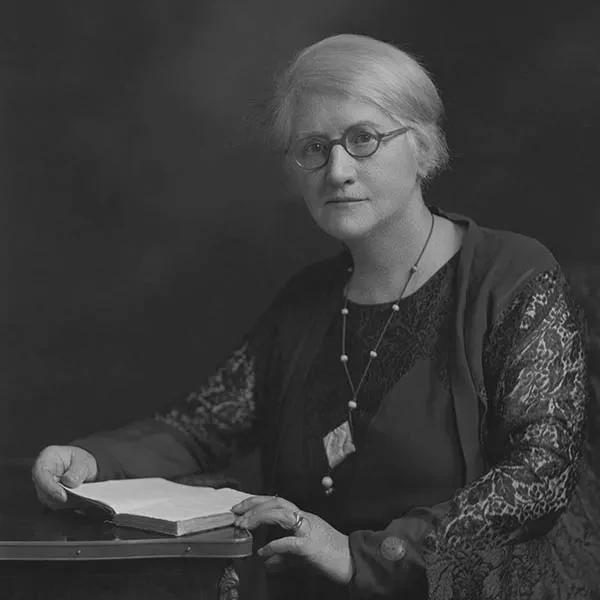 A black and white photograph of Annie Maunder seated with a book.