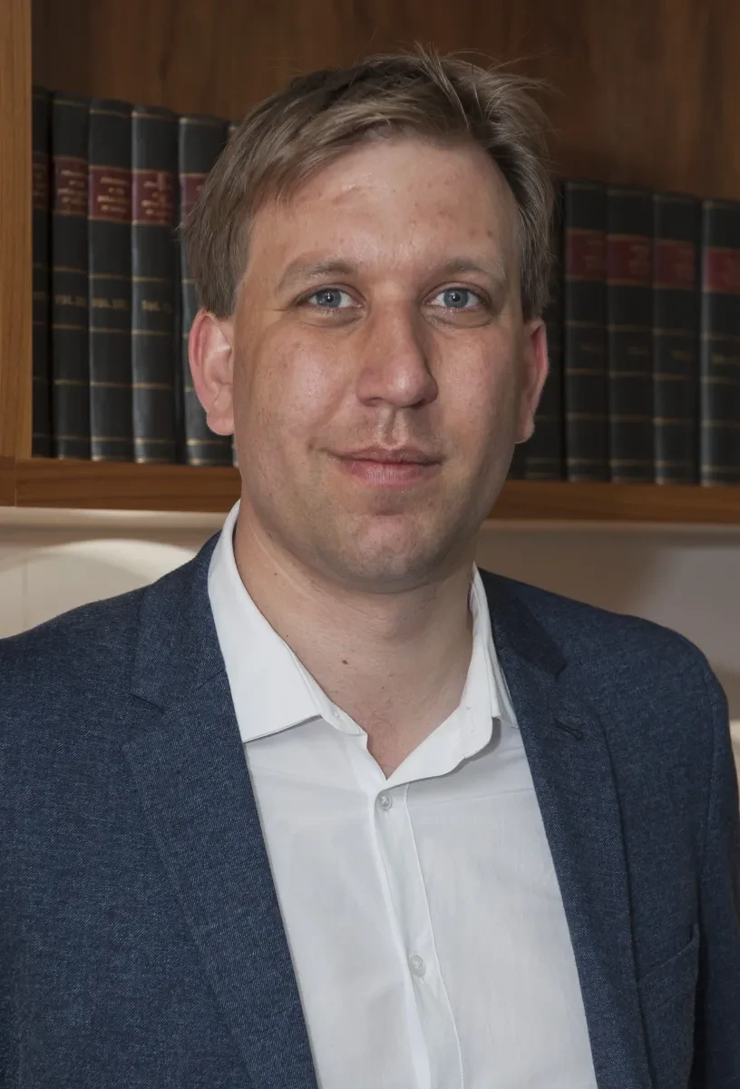 Photograph of Chris Lintott, smiling, wearing white shirt and navy jacket.