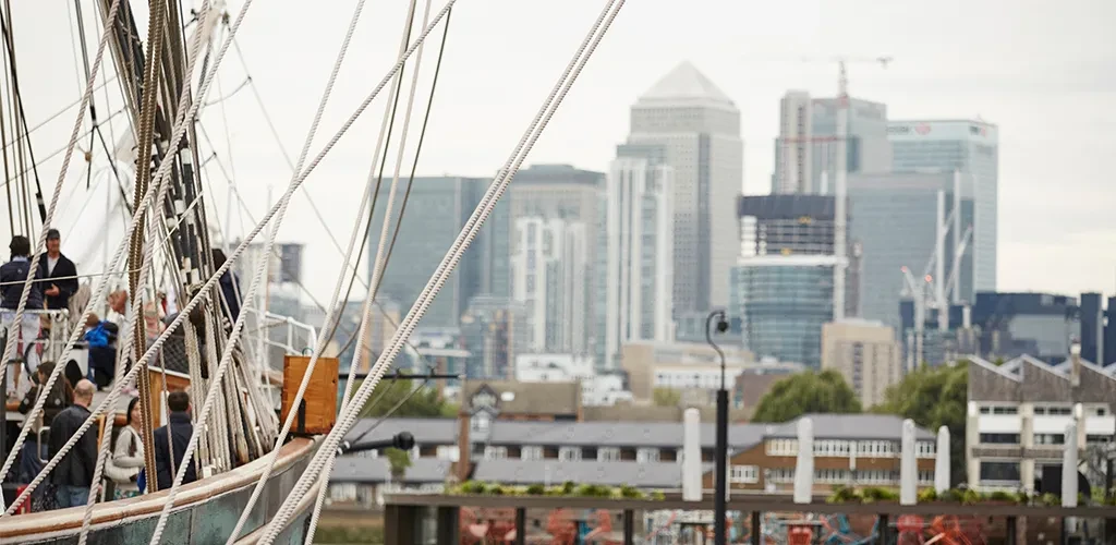 View of the front of Cutty Sark with skyscrapers in the background.