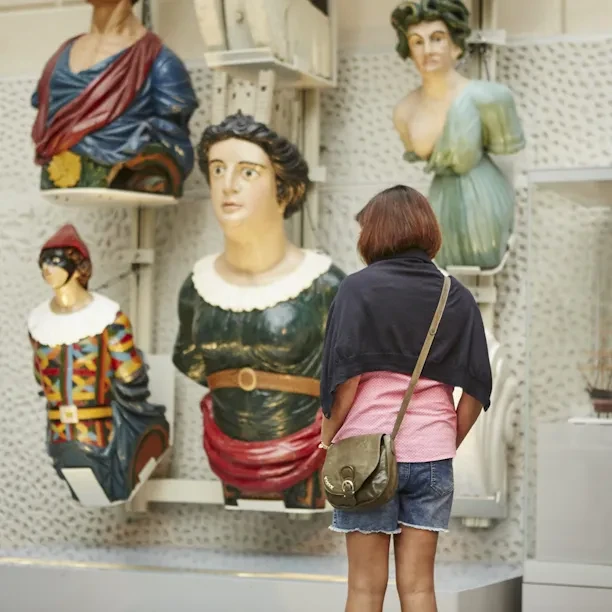 A visitor looking at a display of ship figureheads.