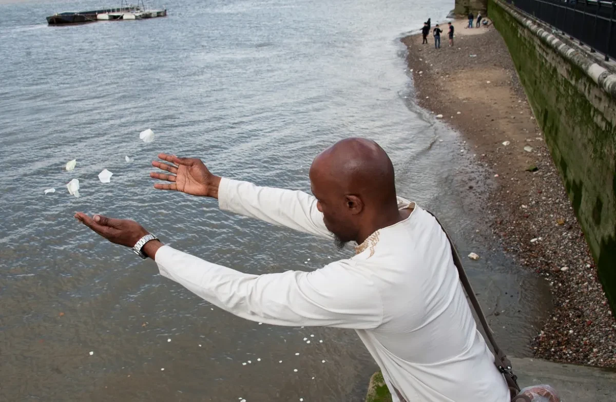 A man scatters petals into a river.