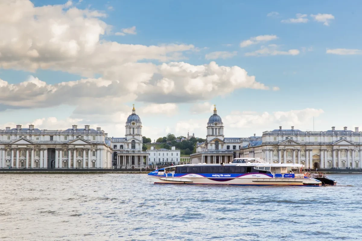 A Thames Clipper boats on the water, passing London landmarks.