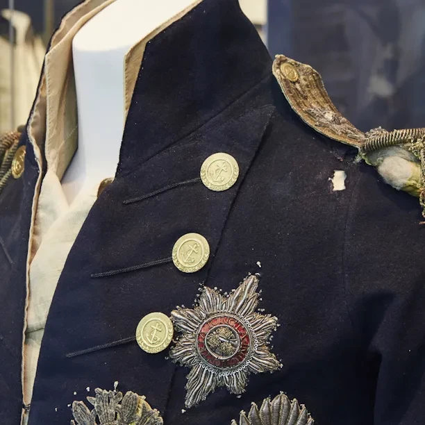 A close-up of Nelson's Trafalgar Coat, it is dark blue with gold details.
