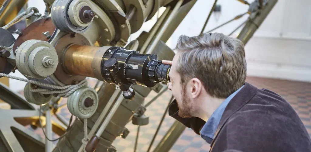 A man looking into a large telescope.