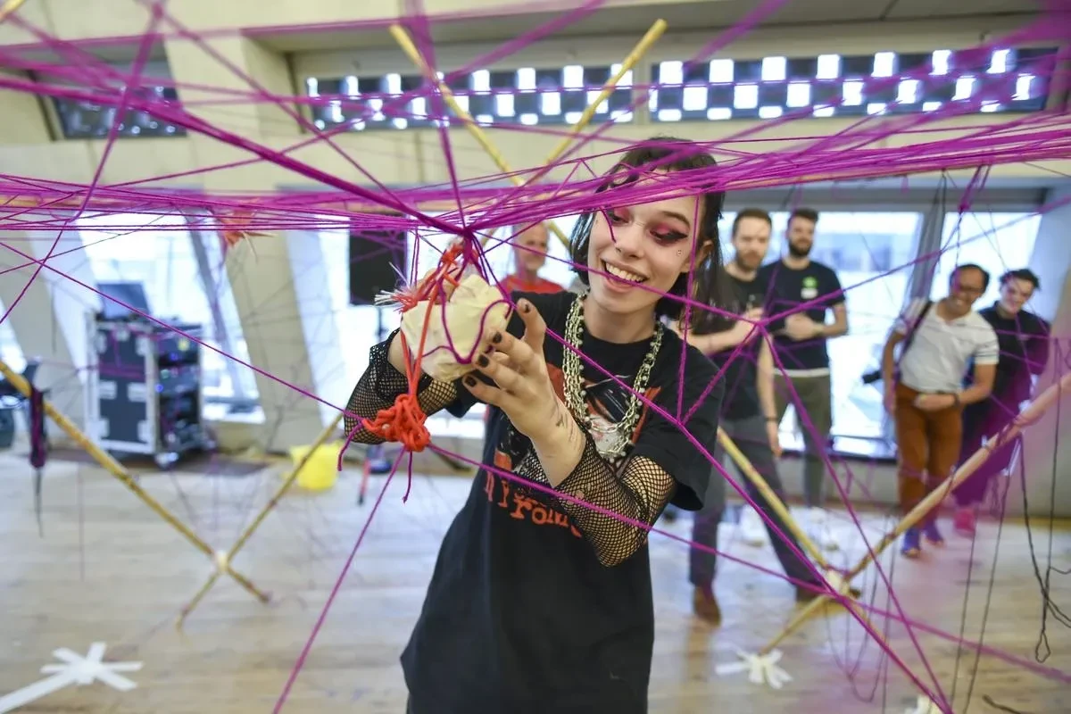 A young person getting creative with coloured string and paper.
