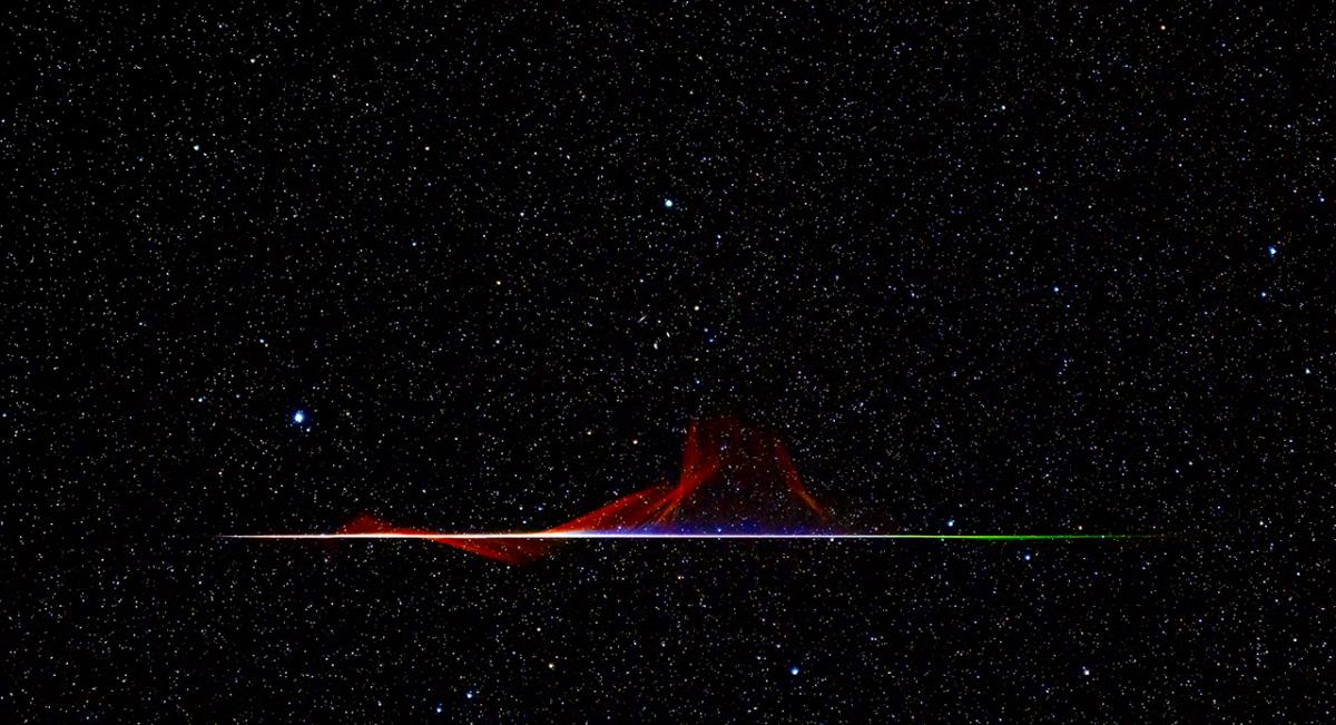 A dark photograph of the night sky with a horizontal flash of purple light from a meteor