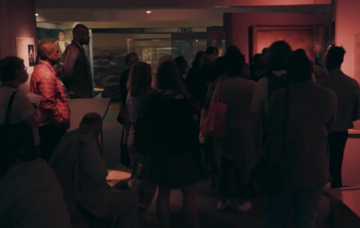 Visitors stand in a museum gallery lit up in red