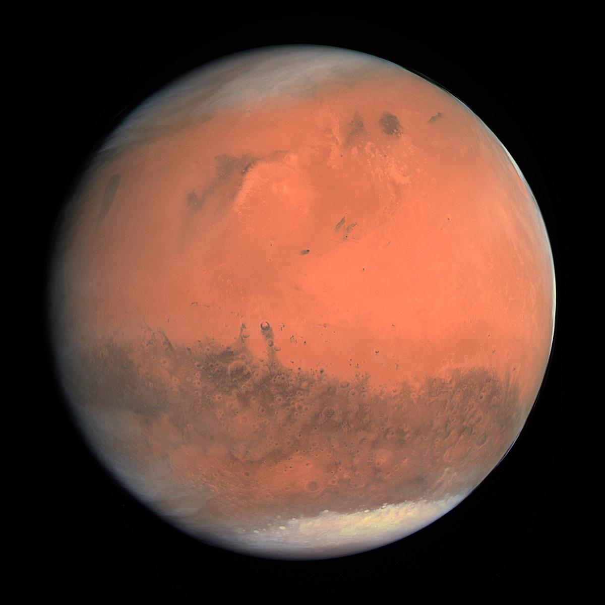 A view of Mars taken by the ESA Rosetta mission on its flyby past the planet. The deep orange red colour of its surface is broken by dark features on the surface and white polar ice caps at the top and bottom of the globe