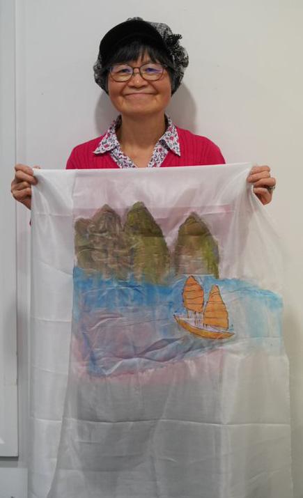 Celia stands holding her artwork