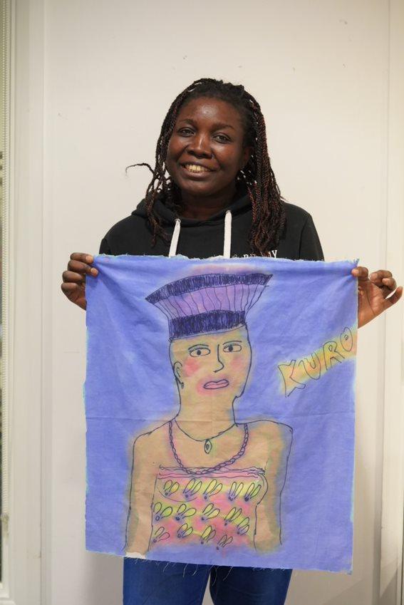 woman holding her painting of a Nigerian woman