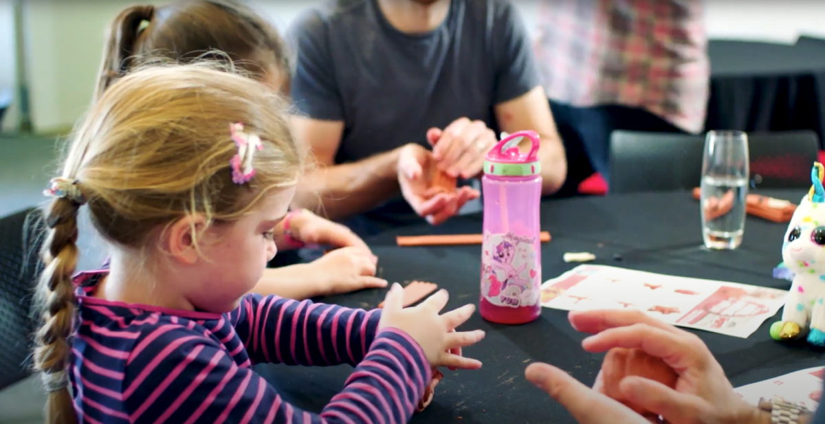 Image of group of children sitting at a round table playing with pieces of clay in their hands