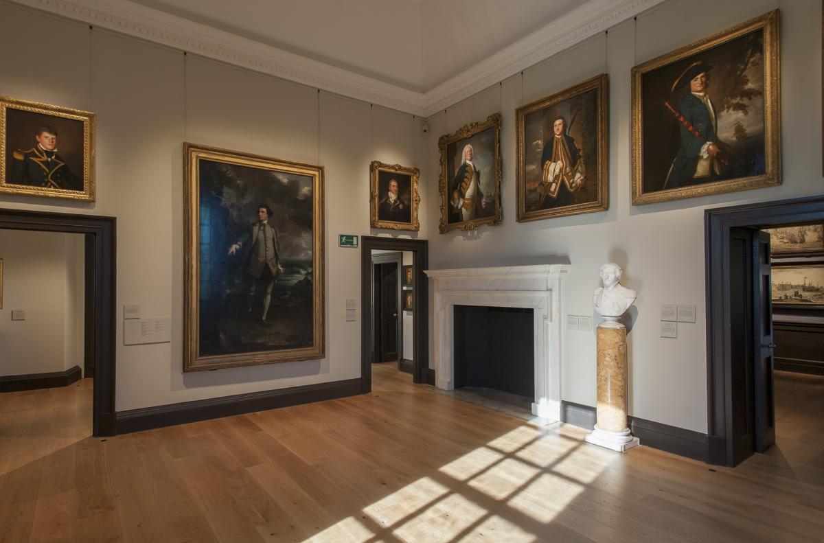 A room hung with paintings and a bust