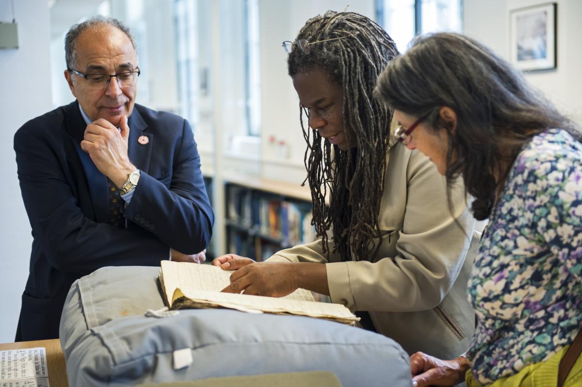 Two men and a woman looking at a manuscript in the Caird Library