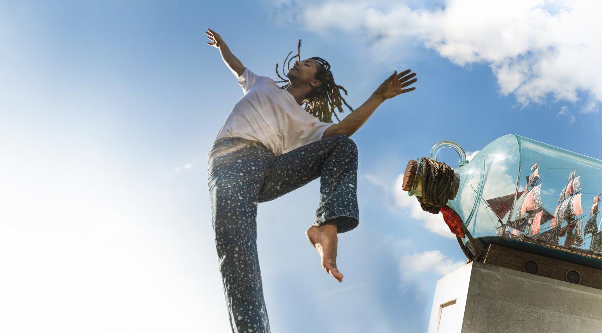 A dance leaps beside Nelson's Ship in a Bottle sculpture