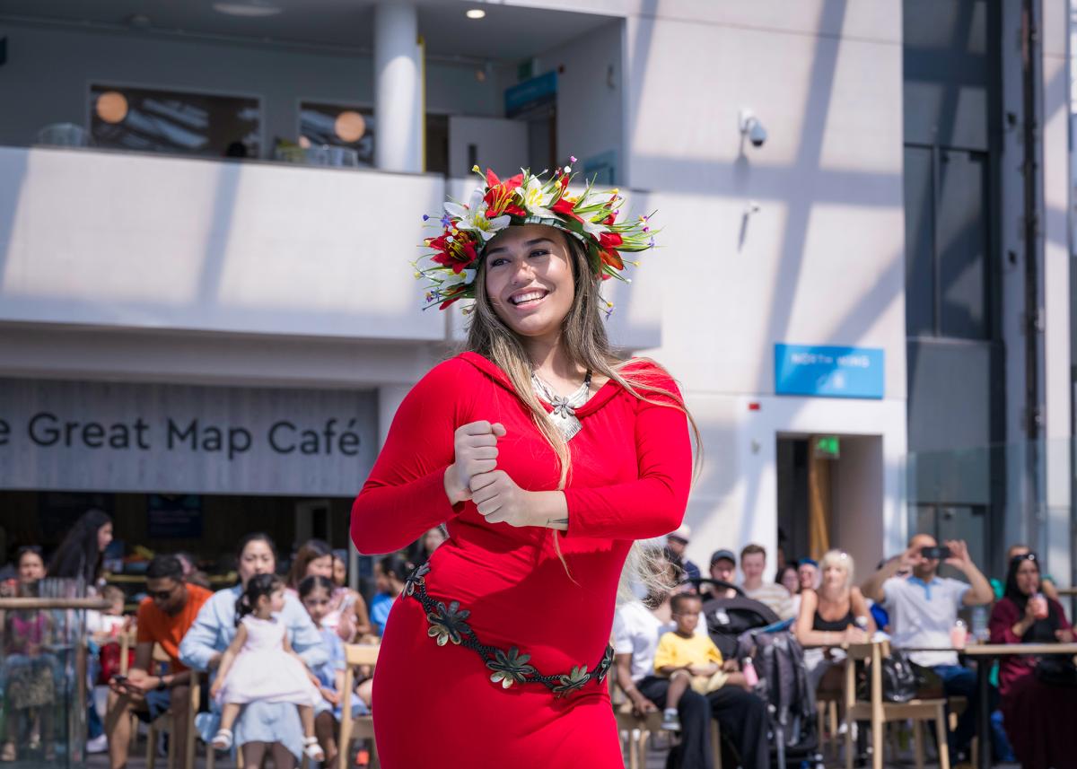 A performer in a red dress and floral headdress performs a dance routine during World Ocean Day at the National Maritime Museum