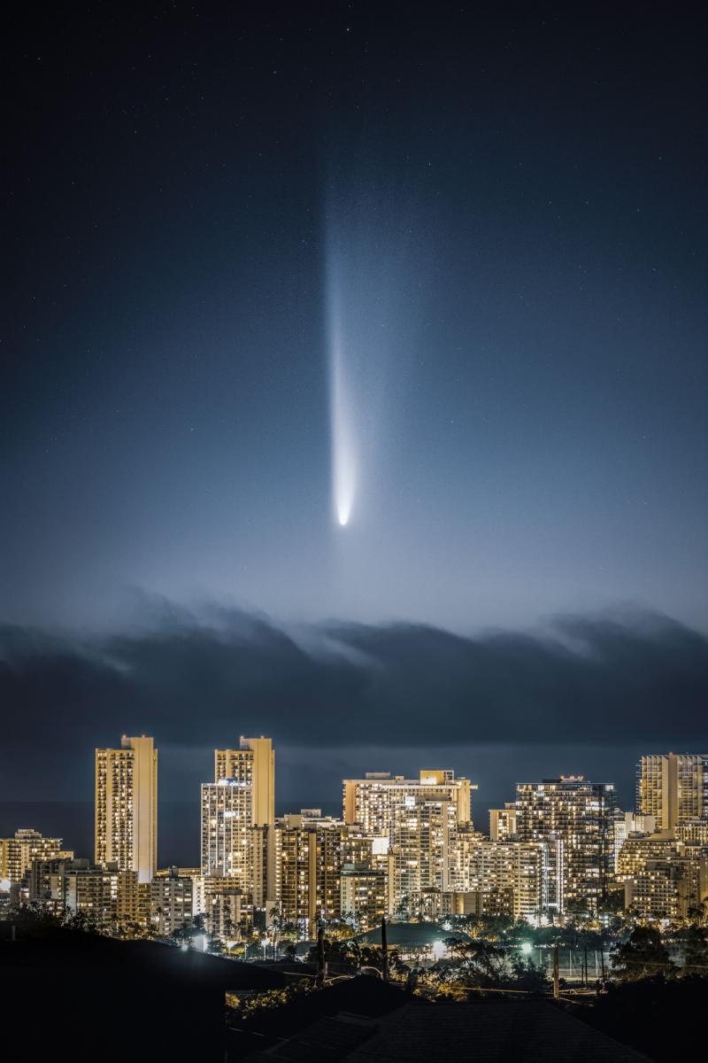 Photo showing lit up city landscape with a large white comet in the sky