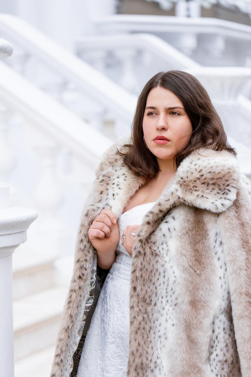 Headshot of Maria Fedulova wearing a brown furry coat against a white backdrop