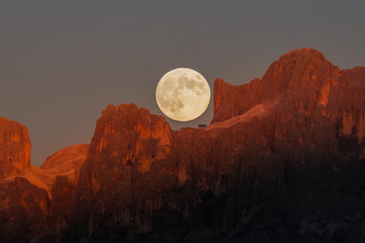 Photo showing top of mountain range in the Dolomites in Italy, with the Moon fitting neatly in a groove in the mountain