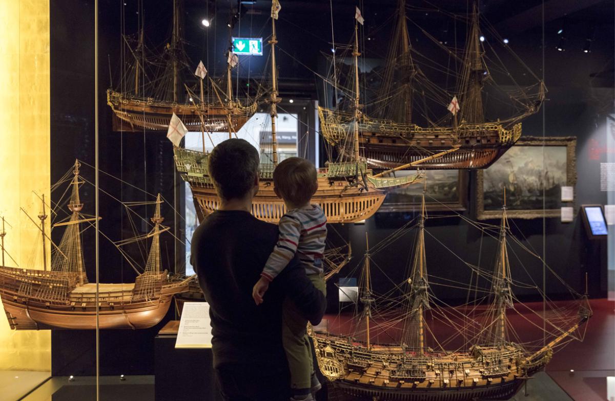 A parent and child looking at model ships.