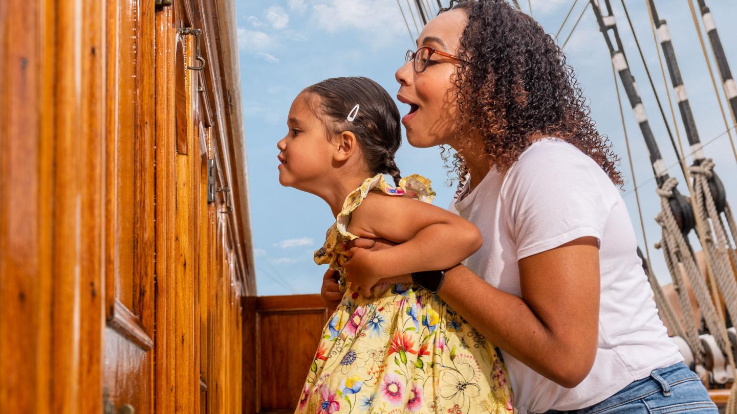 A mother and her child look in through a porthole on the main deck of Cutty Sark