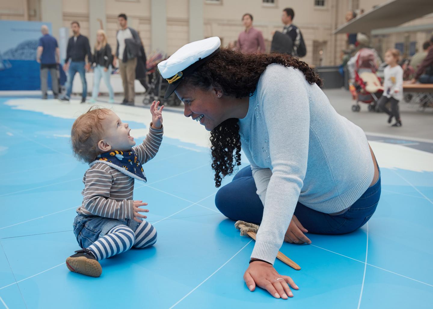 A mother and her child play on the Great Map in the National Maritime Museum. The mother has a sailor hat on