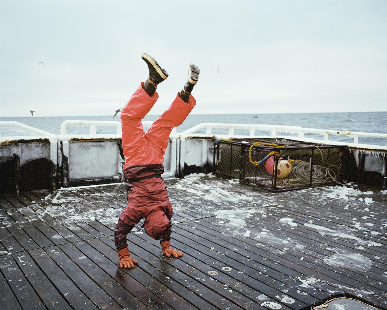 Photo of a person doing a handstand on the deck of a boat at sea