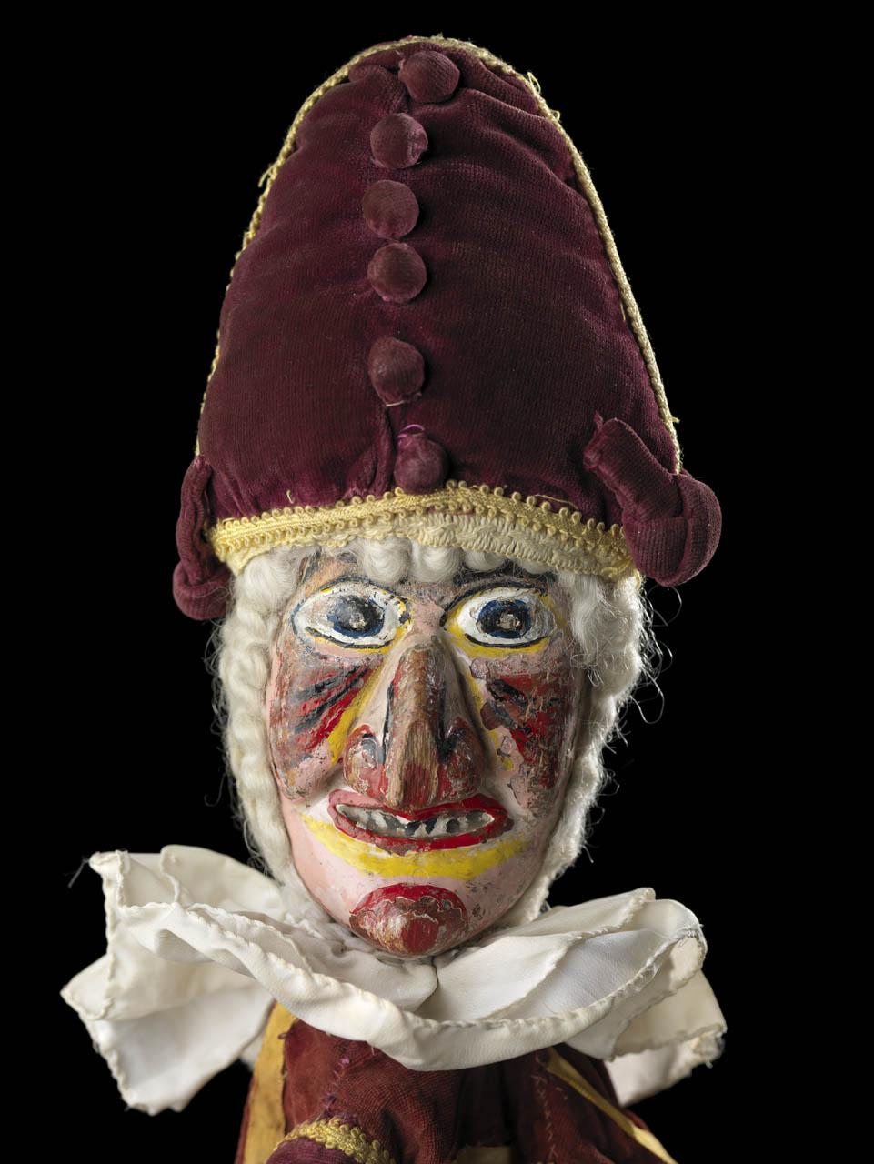 A hand puppet used in Punch and Judy shows. The figure has a red cap, bulbous eyes and painted nose