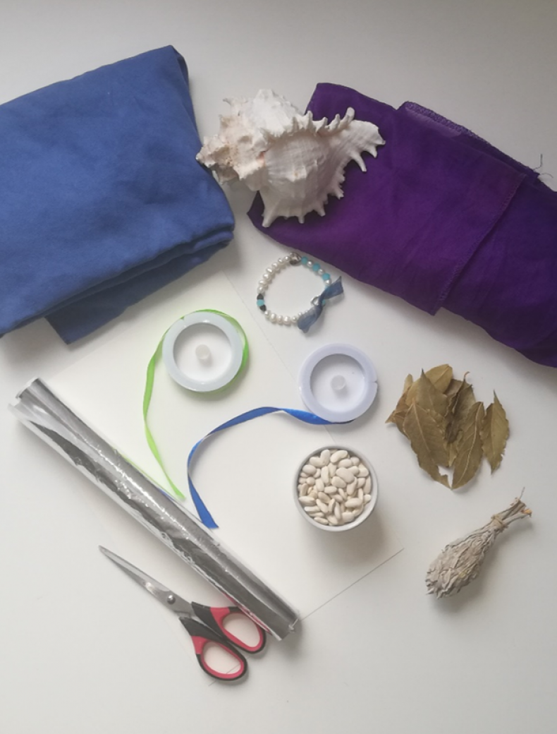 blue fabric, purple fabric, shell, two spools of ribbon, foil, scissors, dried beans, dried leaves, beaded bracelet