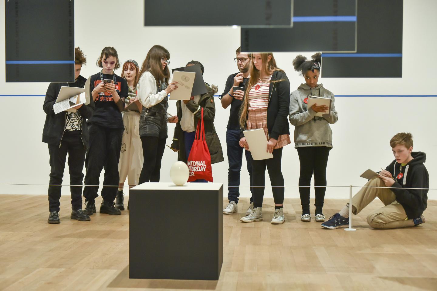 A group of young people are looking at an object which they are drawing