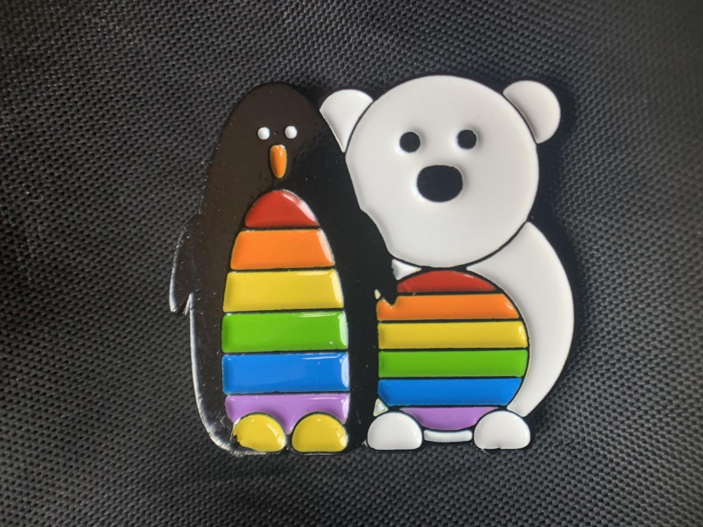 Badge of a penguin and polar bear with rainbow flags on their stomachs