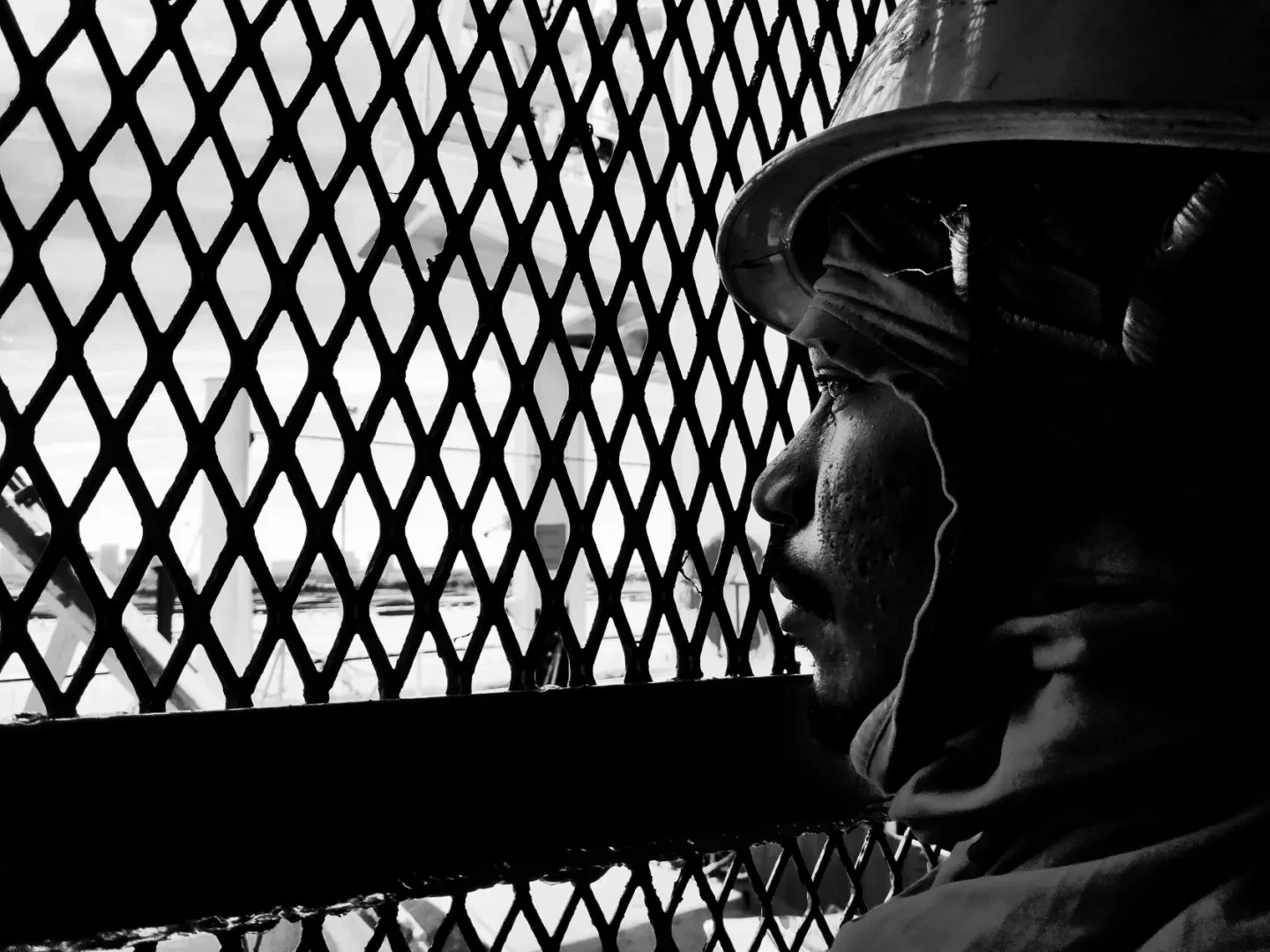 A seafarer behind a grill stares out to sea