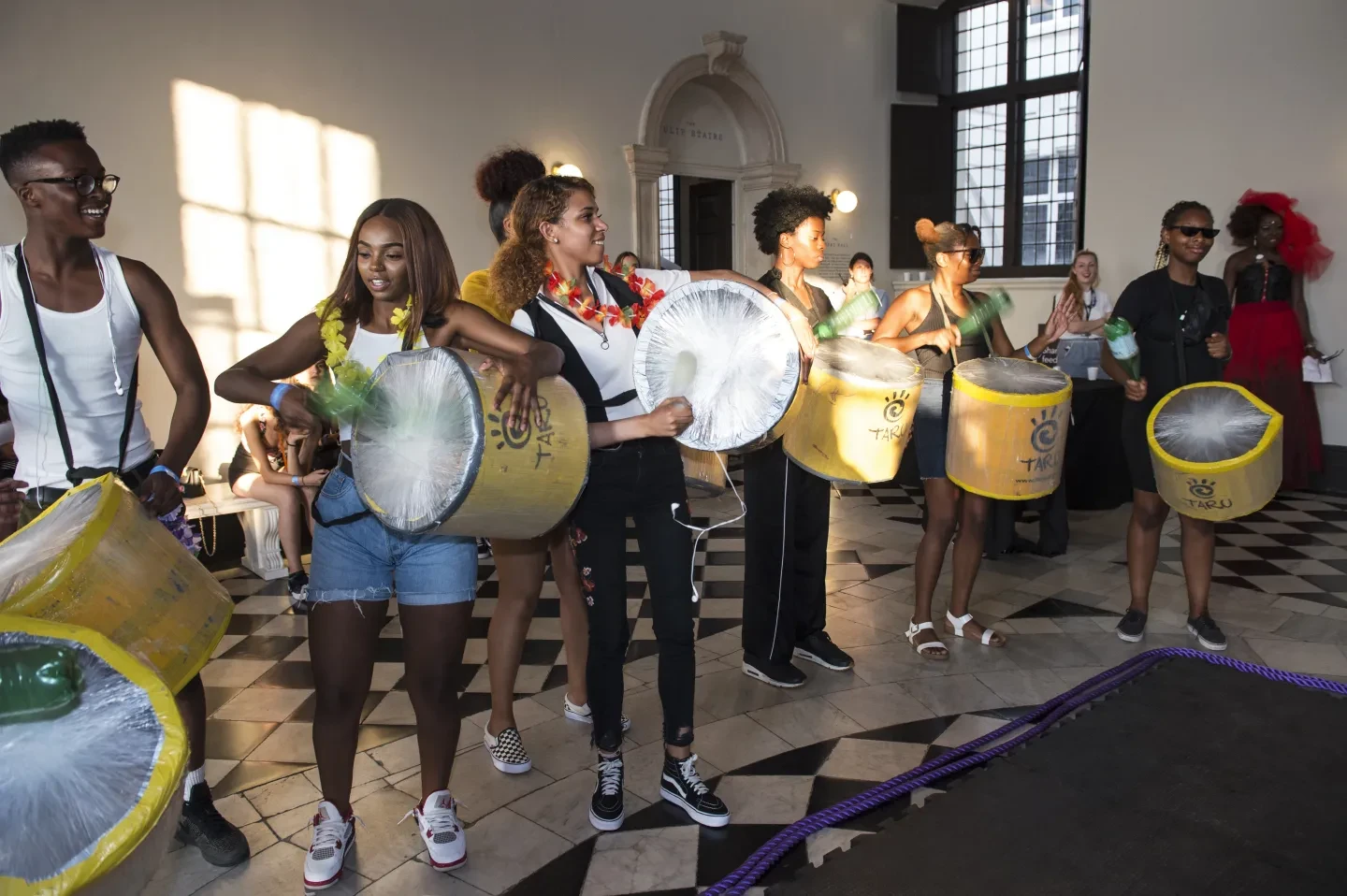 A group of young people playing drums in the queens house