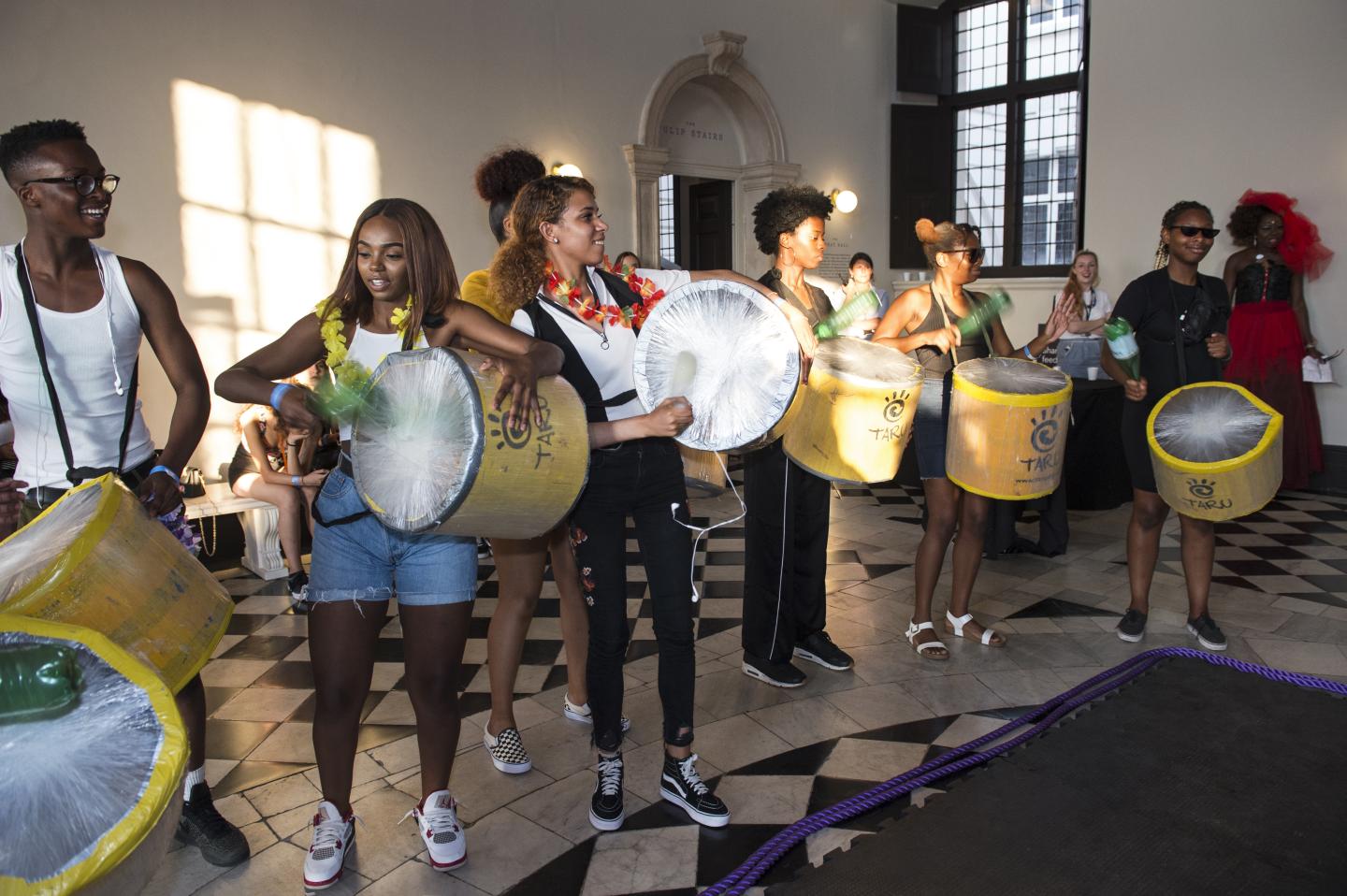 A group of young people playing drums in the queens house